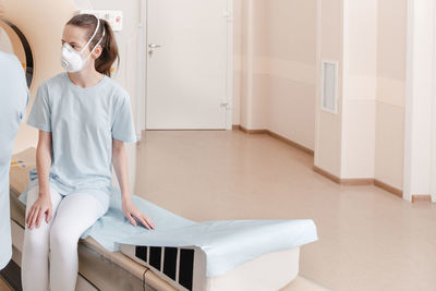 Woman looking down while sitting on white wall