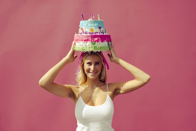 Portrait of smiling young woman against pink background