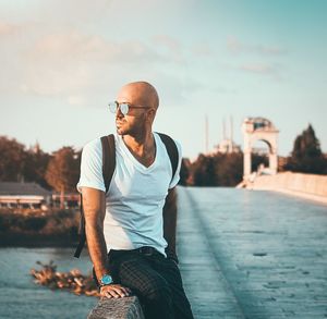 Young man looking away against sky