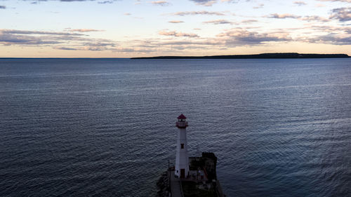 High angle view of lighthouse by sea against cloudy sky during sunset