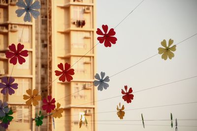 Low angle view of floating wind-chimes in the sky against residential buildings 