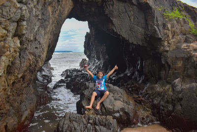 Rear view of man standing on rock by sea