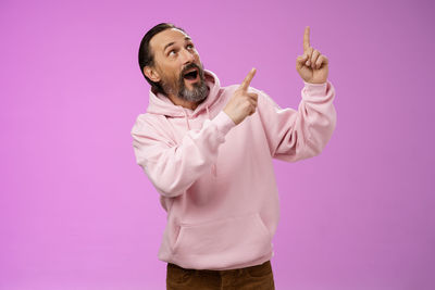 Low section of man standing against pink background