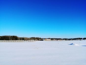 Scenic view of snowcapped field against clear blue sky