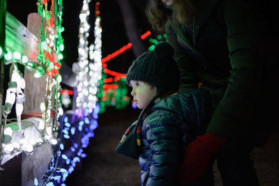 Close-up of boy with mother by illuminated lights