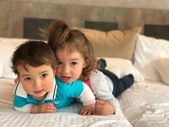 Portrait of cute siblings playing on bed