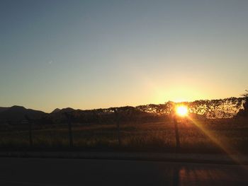 Scenic view of field against clear sky during sunset