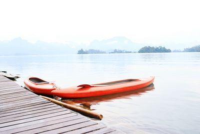 Boat moored on lake against sky