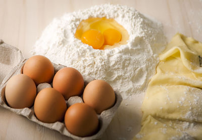 Eggs by flour in carton on table
