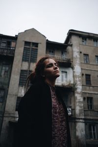Low angle view of woman looking away against building