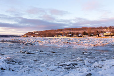 Sunrise view of the st. lawrence river covered in ice with a scattering of houses on the cape 