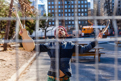 Young man with arms outstretched standing in front of building