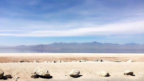 Scenic view of salt lake and mountains against cloudy sky