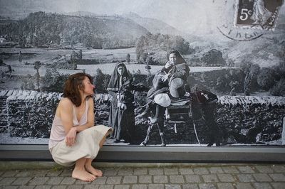 Full length of woman sitting against wall