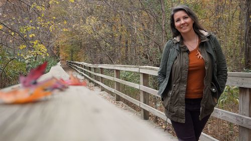 Portrait of smiling young woman standing on footbridge