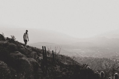 Rear view of man walking on mountain against clear sky