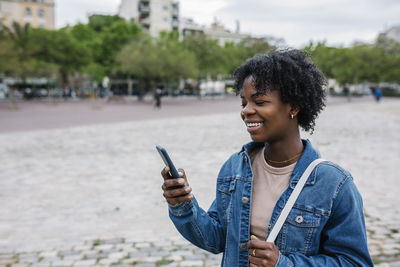 Smiling woman using smart phone in city