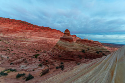 Rock formations on landscape against cloudy sky