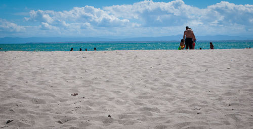 Rear view of people on beach against sky