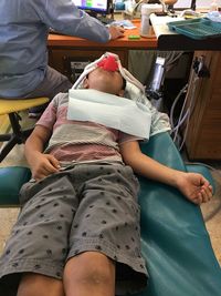 High angle view of boy lying on hospital bed against dentist