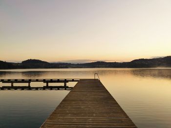 Pier over lake against sky during sunset