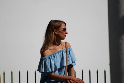 Beautiful young woman standing against wall