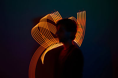 Rear view of man standing against illuminated ferris wheel