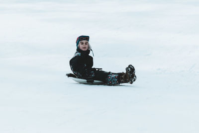 Side view of boy tobogganing on snow