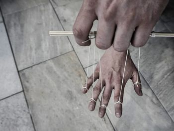 Cropped hands with strings over flooring