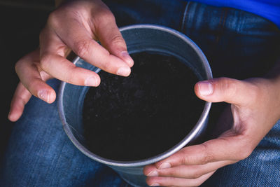 Child hand planting seeds in pots. top view