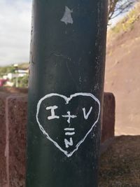 Close-up of information sign on pole against tree trunk