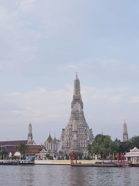 View of buildings by river against sky in city