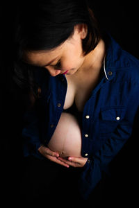 Close-up of young woman against black background