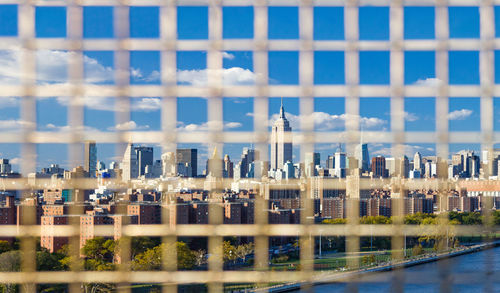 Cityscape against sky seen through metal grate