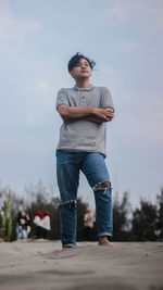 Full length portrait of young man standing against sky