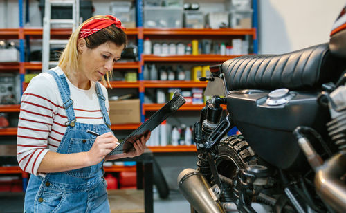 Mechanic woman checking motorcycle on factory