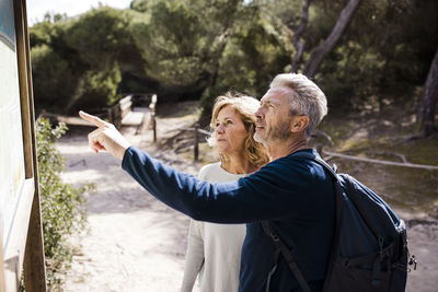Mature woman with man pointing at placard on sunny day