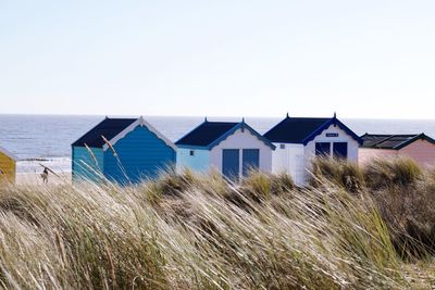 Houses on beach by sea against clear sky