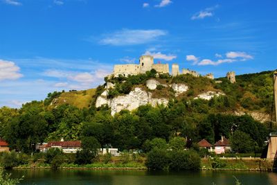 View of castle by river against cloudy sky