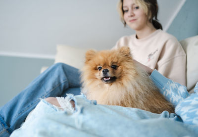 Pomeranian pet on the sofa with teens girls