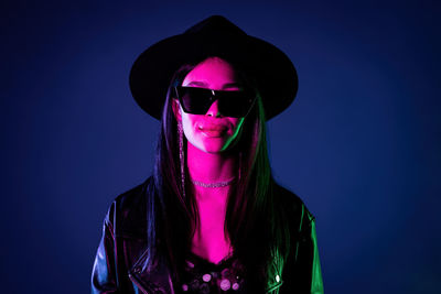 Portrait of young woman wearing sunglasses against blue sky