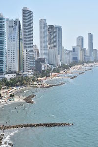 Aerial view of sea and cityscape against clear sky
