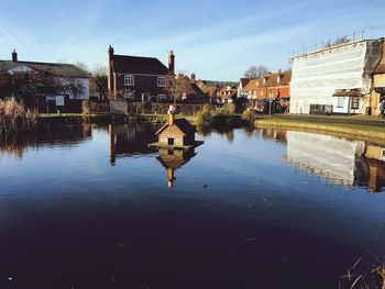 Reflection of houses in lake against sky