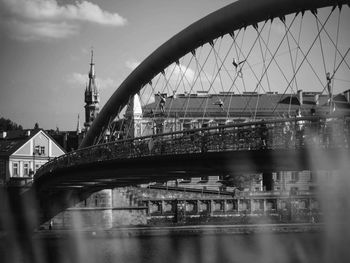 Bridge over river in city against cloudy sky