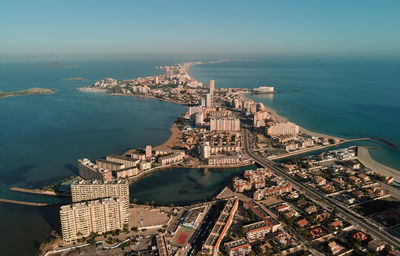 Aerial view of city by sea against sky