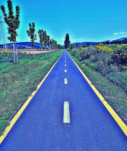 Road amidst trees against blue sky