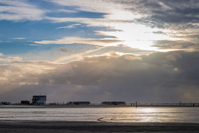 Scenic view of stilt houses and wooden seabridge at low tide north sea beach  against dramatic sky