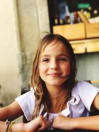 Close-up portrait of smiling girl sitting on chair at home