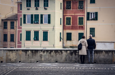 Rear view of people standing on street against building