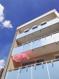 Low angle view of building against sky with pink umbrella 